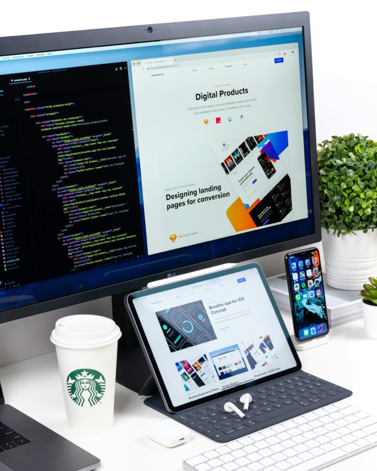 Laptop and monitor displaying backend code and website